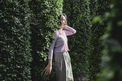 Woman standing by tree against plants