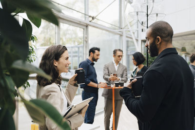 Smiling male and female business people talking while standing in office