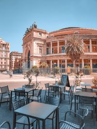 Chairs and tables at sidewalk cafe against buildings in city