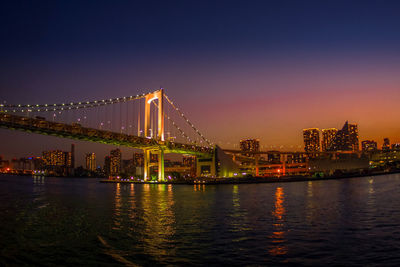 Illuminated bridge over river at night