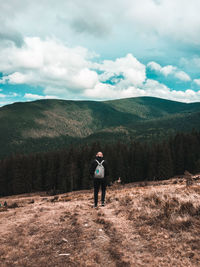 Rear view of man walking on field against sky