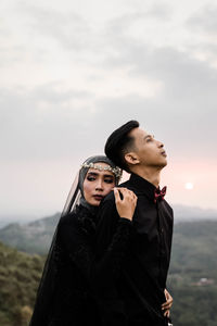 Young couple standing against sky