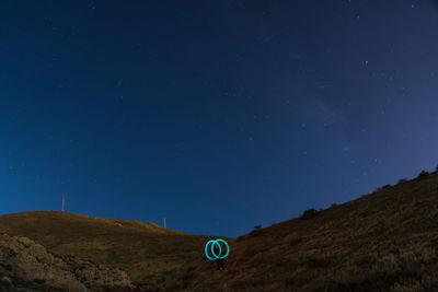 Low angle view of person with light painting on mountain at night