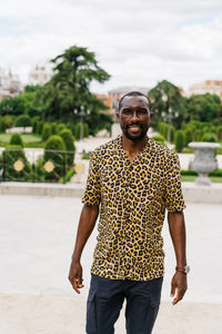 Positive afro american stylish man in european city with electronic device