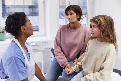 Female doctor talking to girl patient and mother during appointment
