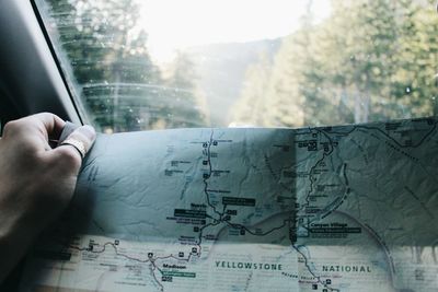 Cropped hand of woman holding world map in car