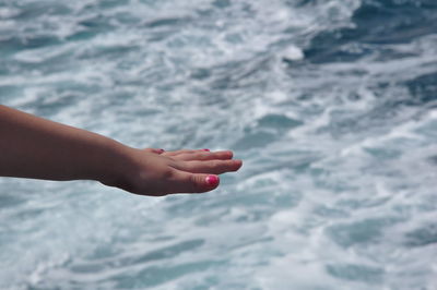 Low section of person hand against sea