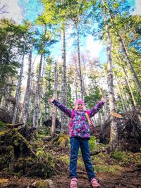 Full length of woman standing by trees in forest