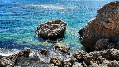 Rock formation in sea against blue sky