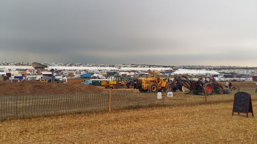 Vehicles on construction site against cloudy sky