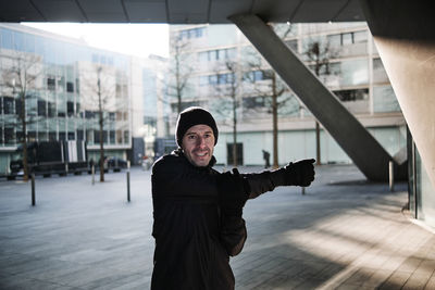 Mature man doing stretching exercise under bridge during sunny day