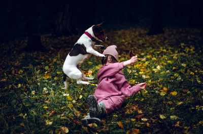 Girl plays with her dog in the autumn forest.