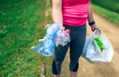 Midsection of woman holding garbage at park