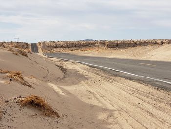 Road amidst desert land against sky