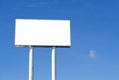 Low angle view of billboard against blue sky