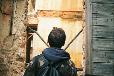 Rear view of man standing by wooden wall