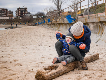 Children playing on sand at beach against sky