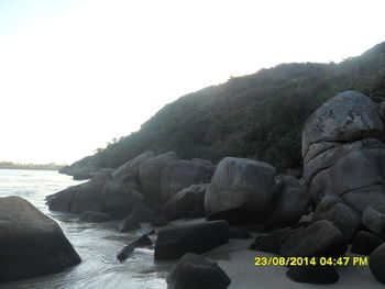 Rocks by sea against clear sky