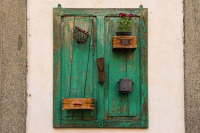 Close-up of an old wooden shutter recycled like a wall decoration with found objects hanging, torino 