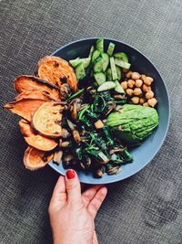 High angle view of hand holding food in bowl on tablecloth