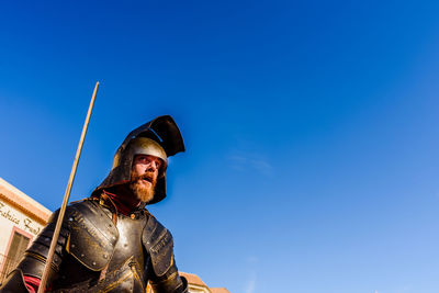 Low angle view of man looking away against blue sky