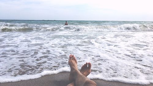 Low section of man on beach against sky