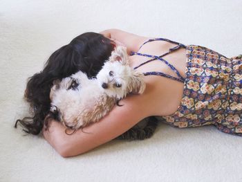 Midsection of woman with puppy sitting at home