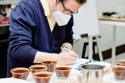 Midsection of man writing on document at cafe