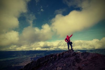 Rear view of man standing on mountain against sky