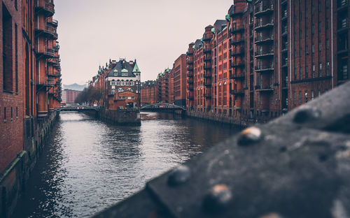 Canal amidst buildings in city against sky