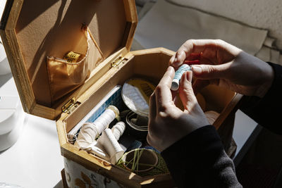 Crop female sewer keeps her sewing utensils in a sewing box at home