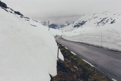 Snow covered road by mountain against sky