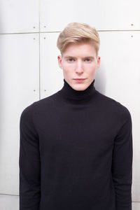 Portrait of young man standing against wall