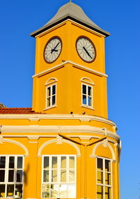 Low angle view of yellow building against blue sky