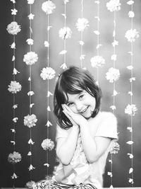 Portrait of happy girl by garlands hanging against wall