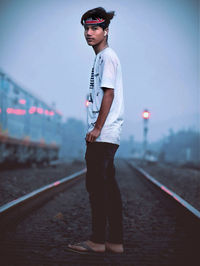 Portrait of young man standing on railroad track