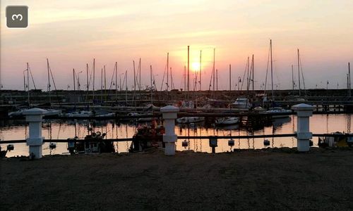 Boats moored at harbor during sunset