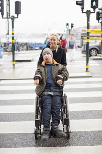 Caretaker pushing disabled man on wheelchair while crossing road