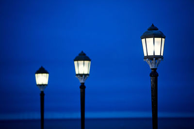 Illuminated street light in row against blue sky during dusk