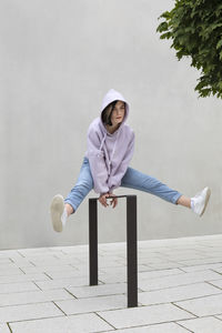 Girl jumping over metal by wall