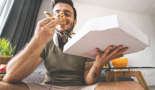 Midsection of man holding food while sitting on table at home