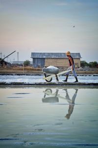 Side view of man standing on shore against sky