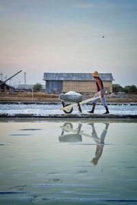 Full length of worker walking with wheelbarrow at salt lake