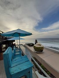 Chairs by swimming pool on beach against sky