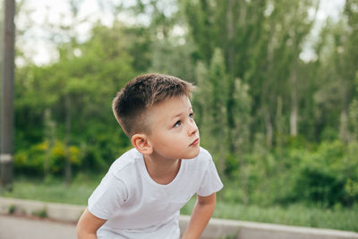 Portrait of boy looking away against trees