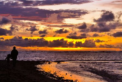 Silhouette man standing on beach against sky during sunset