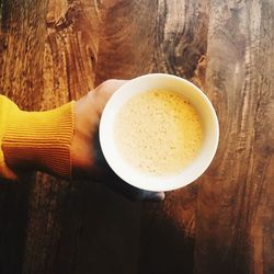 Close-up of hand holding tea cup on table