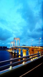 Light trails on bridge over road against blue sky