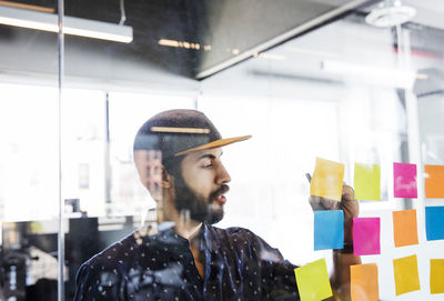 Businessman giving presentation in meeting room seen through glass