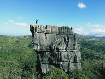 Woman standing on rock formation against sky